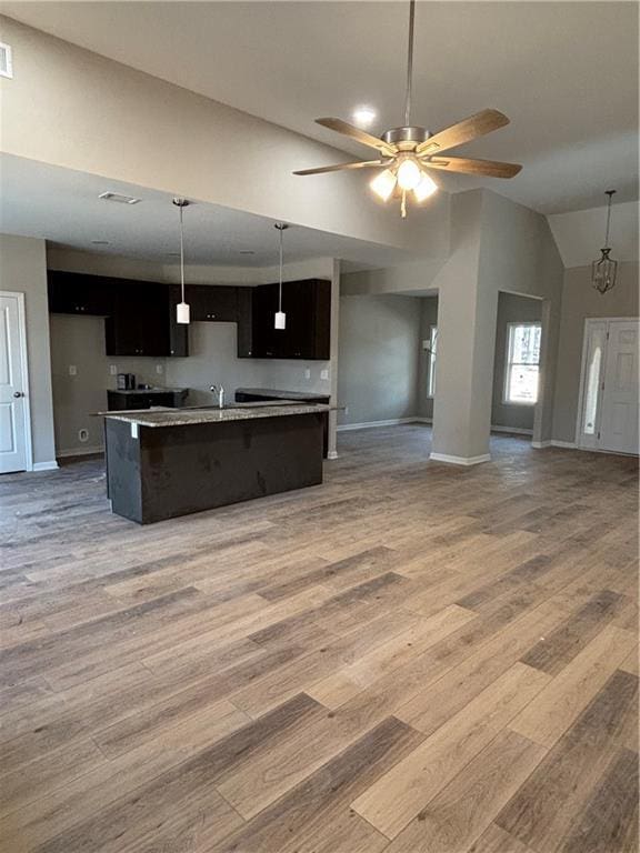 kitchen featuring sink, vaulted ceiling, hardwood / wood-style flooring, ceiling fan, and a kitchen island with sink