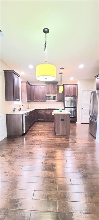 kitchen featuring pendant lighting, dark brown cabinetry, dark hardwood / wood-style floors, and appliances with stainless steel finishes