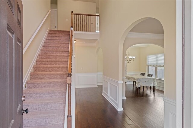 stairs featuring crown molding, wood-type flooring, and a chandelier