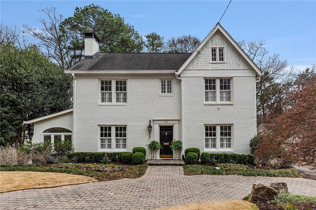 view of front of home with a chimney and brick siding