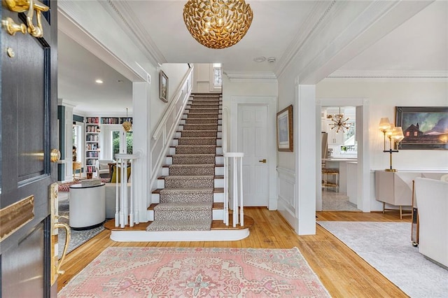 foyer with ornamental molding, stairway, and wood finished floors