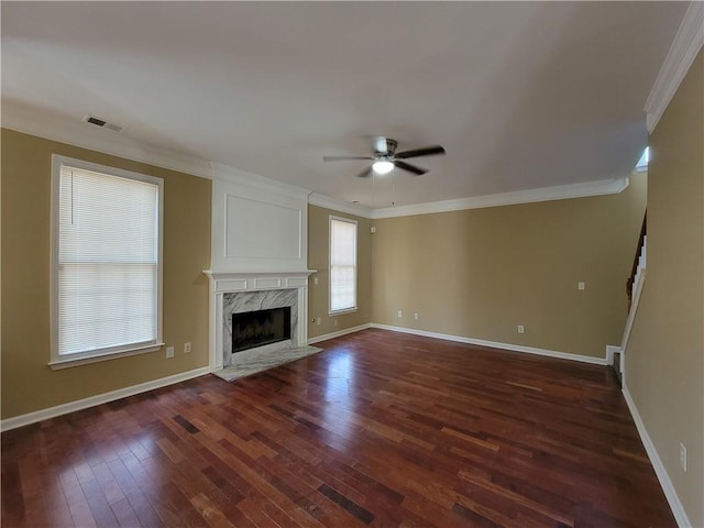 unfurnished living room featuring crown molding, dark wood-type flooring, ceiling fan, and a high end fireplace