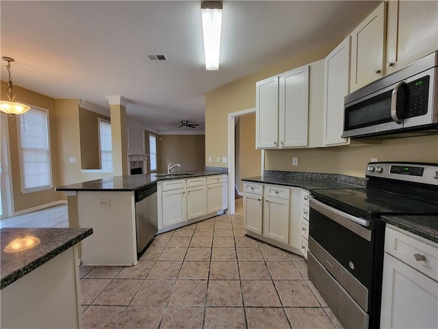 kitchen featuring pendant lighting, sink, light tile patterned floors, white cabinetry, and stainless steel appliances