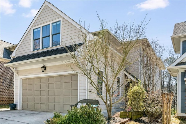 view of front of property featuring driveway, an attached garage, and roof with shingles