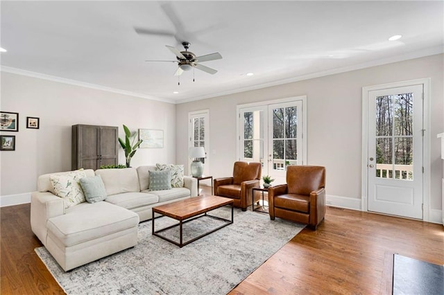 living area featuring crown molding, wood finished floors, and baseboards