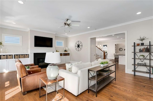 living area with a glass covered fireplace, a healthy amount of sunlight, stairway, and wood finished floors