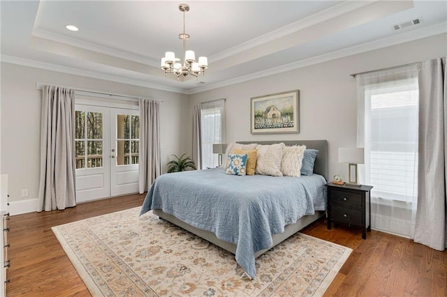 bedroom featuring visible vents, a raised ceiling, and wood finished floors