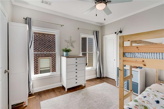 bedroom with wood finished floors, visible vents, baseboards, ceiling fan, and crown molding