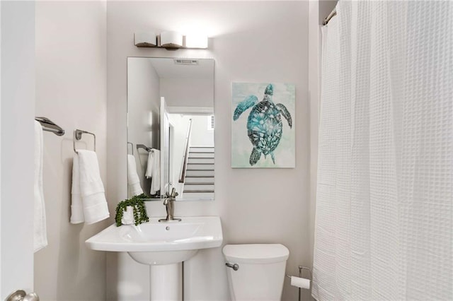 bathroom with a shower with curtain, toilet, and visible vents