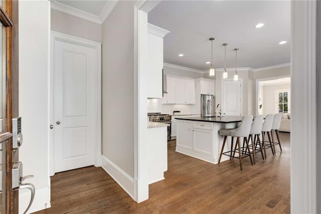 kitchen with a kitchen breakfast bar, dark wood-style floors, appliances with stainless steel finishes, and ornamental molding