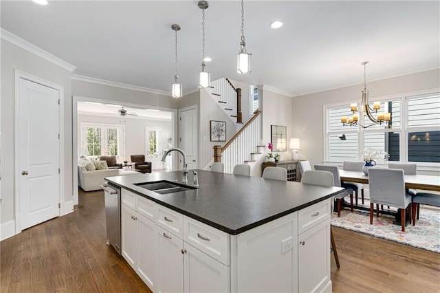 kitchen featuring dark countertops, dark wood finished floors, ornamental molding, and a sink