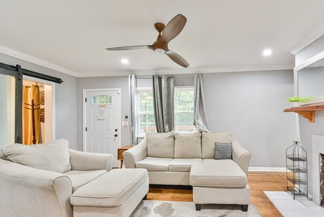 living area with recessed lighting, a barn door, light wood-style floors, ceiling fan, and ornamental molding