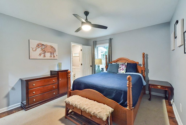 bedroom with wood finished floors, connected bathroom, a ceiling fan, and baseboards