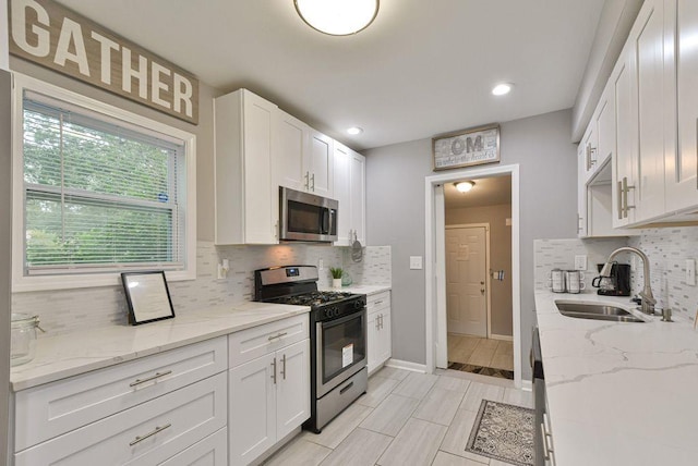 kitchen with tasteful backsplash, white cabinets, stainless steel appliances, and a sink