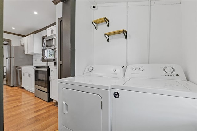 laundry room with crown molding, independent washer and dryer, and light hardwood / wood-style flooring