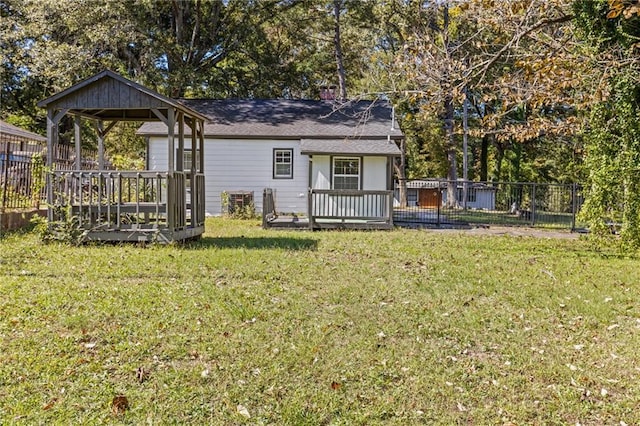 rear view of property featuring a deck, a gazebo, and a lawn