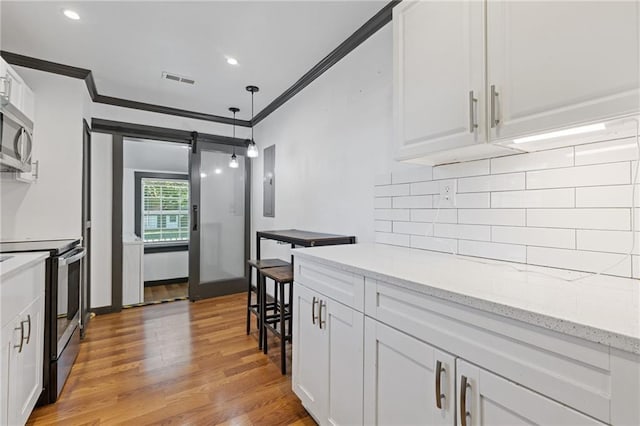 kitchen with light hardwood / wood-style floors, appliances with stainless steel finishes, light stone countertops, crown molding, and white cabinets