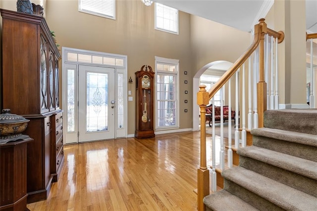 foyer featuring a wealth of natural light, light hardwood / wood-style flooring, crown molding, and a high ceiling