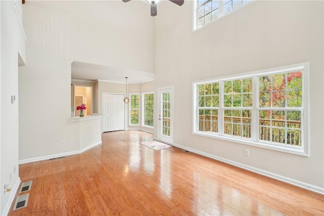 unfurnished living room with a high ceiling, light hardwood / wood-style floors, and ceiling fan