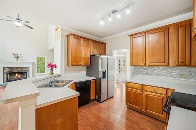 kitchen featuring kitchen peninsula, light wood-type flooring, ornamental molding, black appliances, and sink