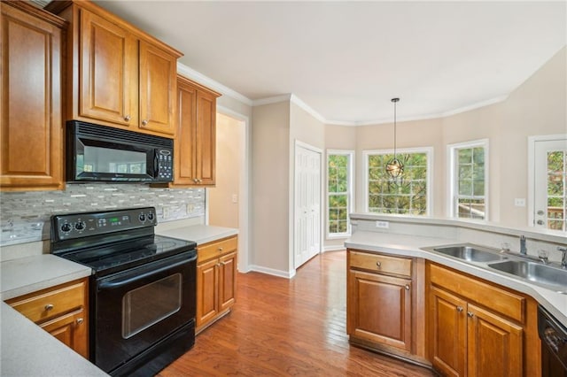 kitchen featuring black appliances, sink, decorative light fixtures, ornamental molding, and light hardwood / wood-style flooring