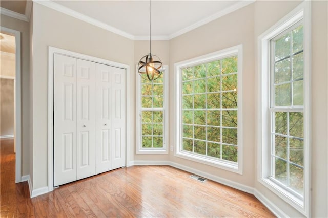 unfurnished dining area with light wood-type flooring, ornamental molding, and plenty of natural light