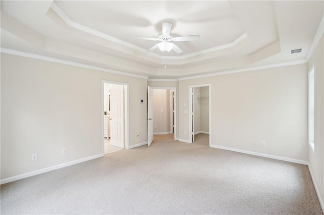 carpeted spare room featuring crown molding, a tray ceiling, and ceiling fan