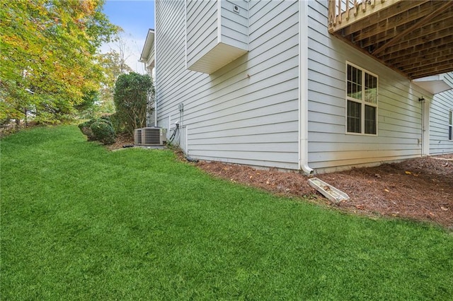 view of side of home with central AC and a yard