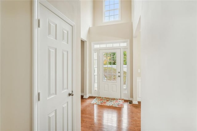 foyer with a towering ceiling and light wood-type flooring