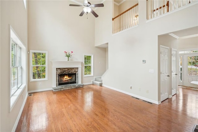 unfurnished living room with ornamental molding, wood-type flooring, a high ceiling, and a wealth of natural light