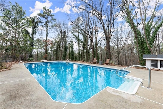 view of pool featuring a diving board, an outbuilding, and a patio area