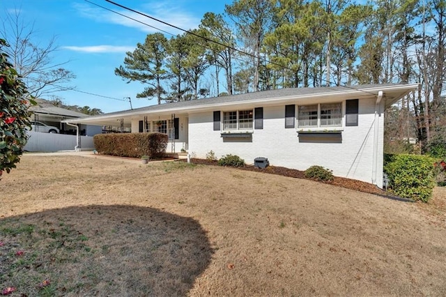 ranch-style home featuring fence, a front lawn, and brick siding