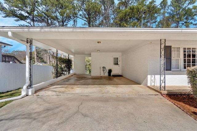 view of parking / parking lot with driveway, a carport, and fence