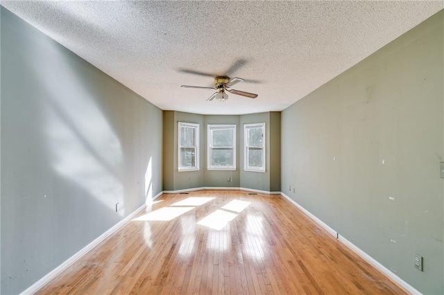 spare room with ceiling fan, a textured ceiling, and light wood-type flooring