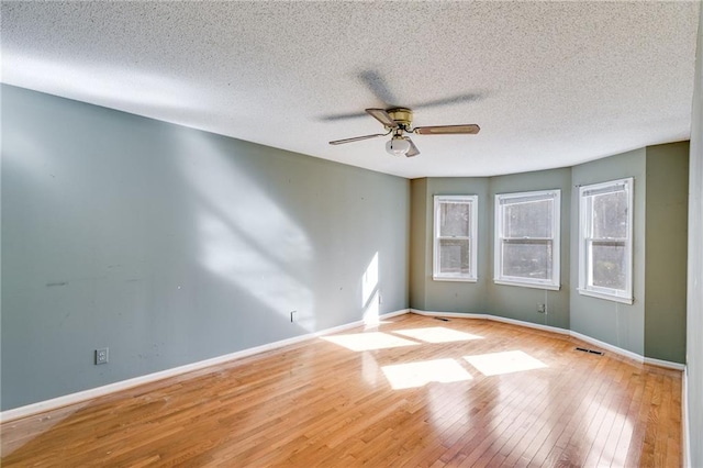 empty room with a textured ceiling, light wood-type flooring, and ceiling fan