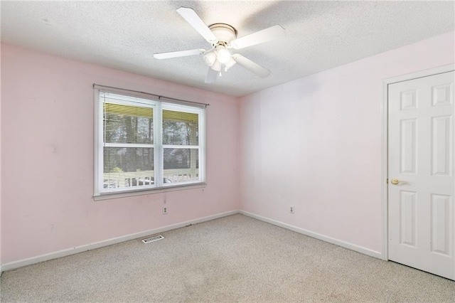 carpeted empty room featuring ceiling fan and a textured ceiling