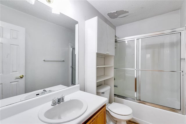 full bathroom with vanity, a textured ceiling, toilet, and bath / shower combo with glass door