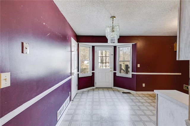 foyer featuring a textured ceiling and a notable chandelier