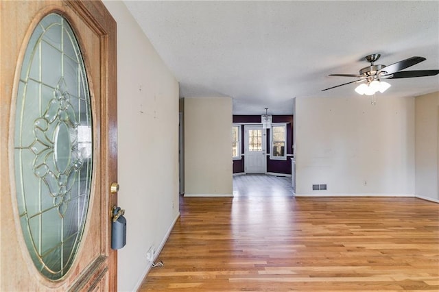 foyer entrance featuring ceiling fan, a textured ceiling, and light wood-type flooring