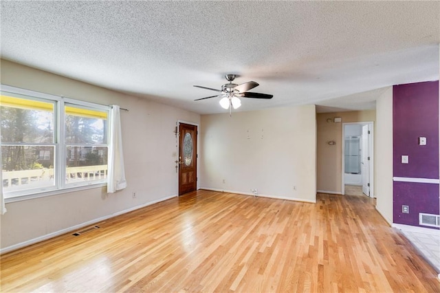 empty room featuring ceiling fan, light hardwood / wood-style floors, and a textured ceiling