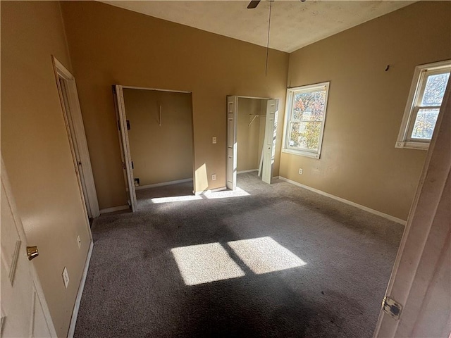 unfurnished bedroom featuring ceiling fan, carpet floors, and two closets