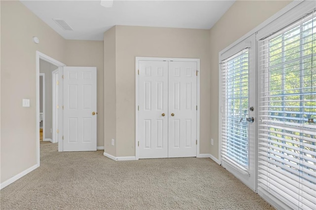 unfurnished bedroom with carpet flooring, baseboards, visible vents, and a closet