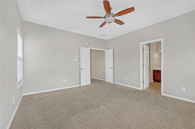unfurnished bedroom with baseboards, ceiling fan, light carpet, and ensuite bath