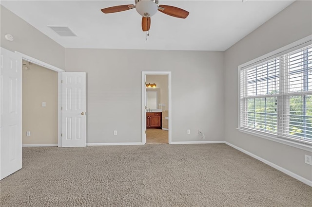 unfurnished bedroom featuring ceiling fan, visible vents, baseboards, light carpet, and ensuite bath