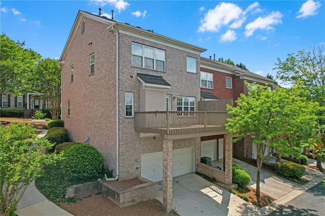 back of property with brick siding, a garage, a balcony, and concrete driveway