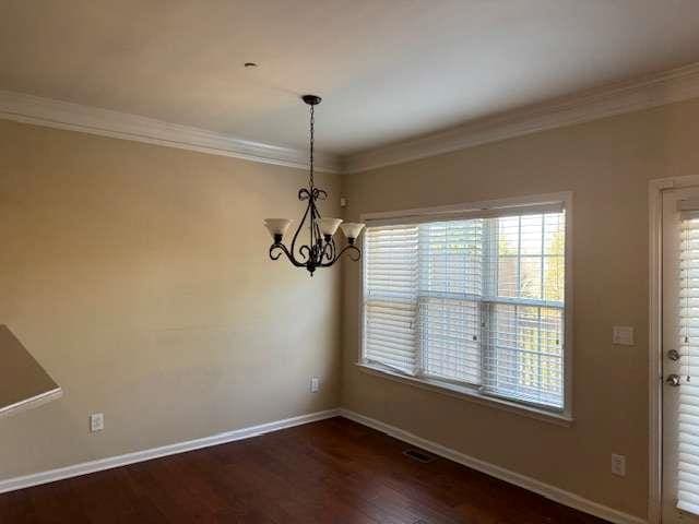 unfurnished dining area with baseboards, an inviting chandelier, dark wood-style floors, and ornamental molding