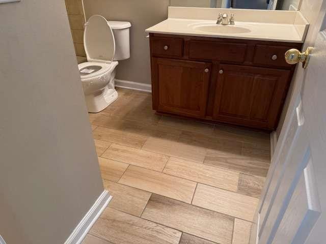 bathroom with vanity, baseboards, toilet, and wood finished floors