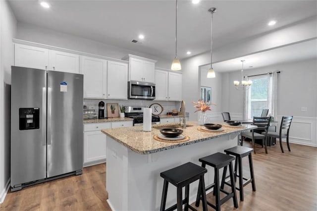 1311 Park Center Cir, Austell, GA 30168 - kitchen with appliances with stainless steel finishes, white cabinetry, wood finished floors, a breakfast bar, and an island with sink