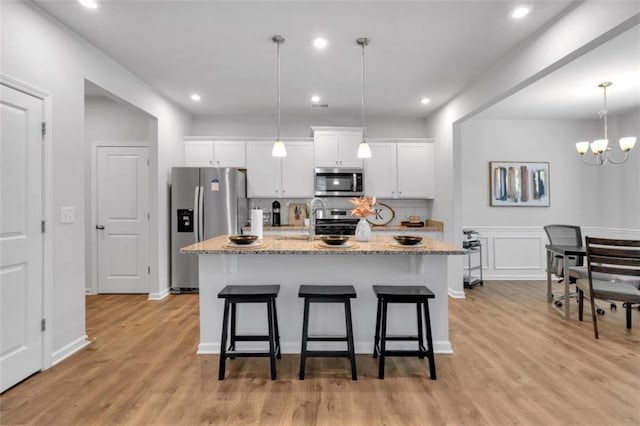 1311 Park Center Cir, Austell, GA 30168 - kitchen featuring appliances with stainless steel finishes, a kitchen breakfast bar, white cabinetry, a kitchen island with sink, and a chandelier