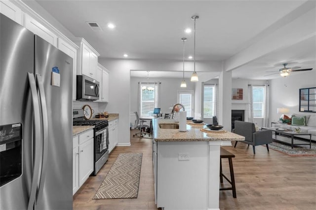 1311 Park Center Cir, Austell, GA 30168 - kitchen featuring stainless steel appliances, a kitchen breakfast bar, an island with sink, white cabinetry, and light wood-style floors
